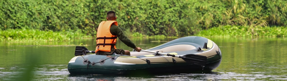 мужчина в спасательном жилете едит по реке на лодке